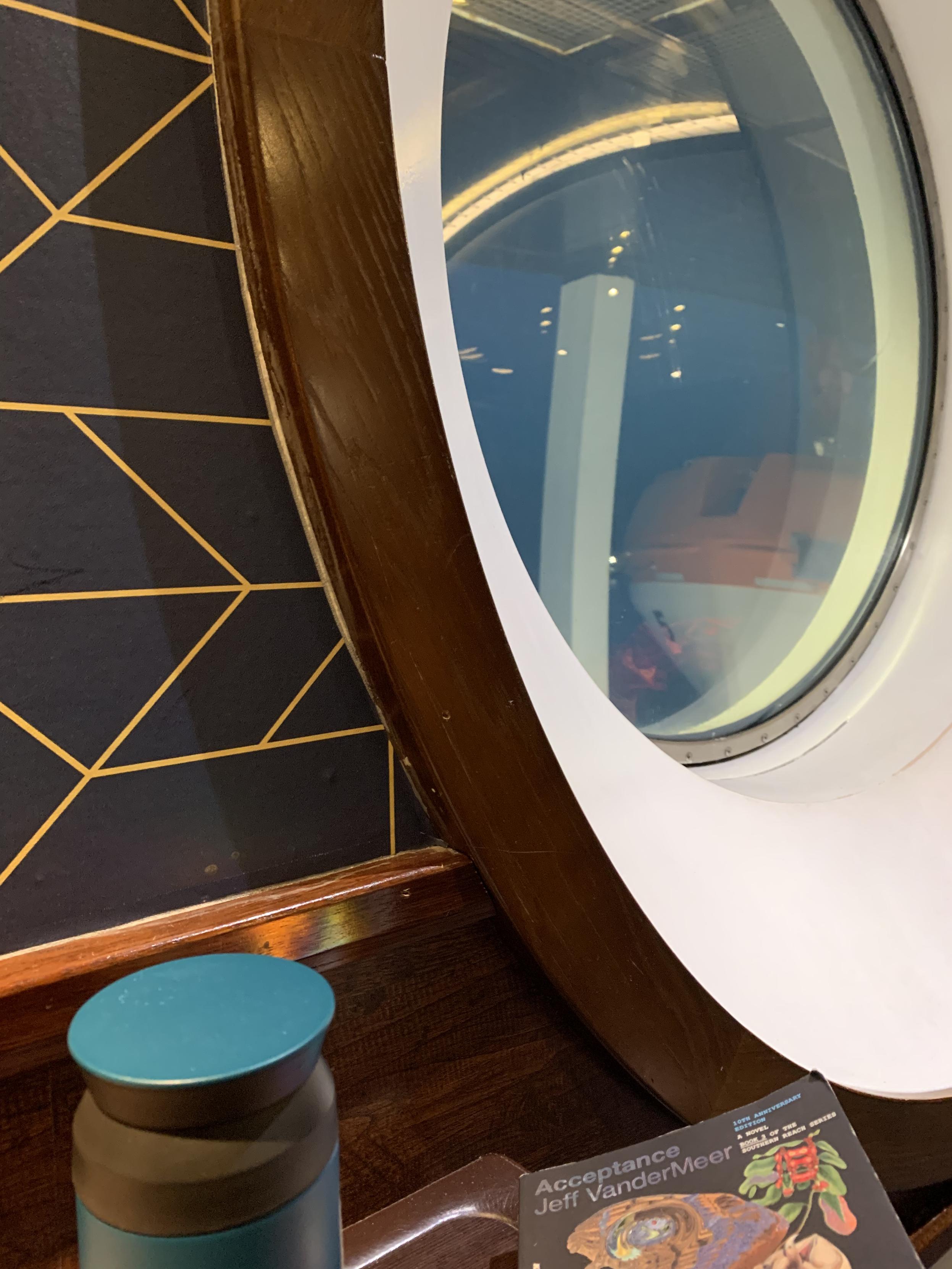 portal of norwegian ferry’s porthole window with portal of teal metal coffee thermos plus portal of jeff vandermeer’s book “acceptance”