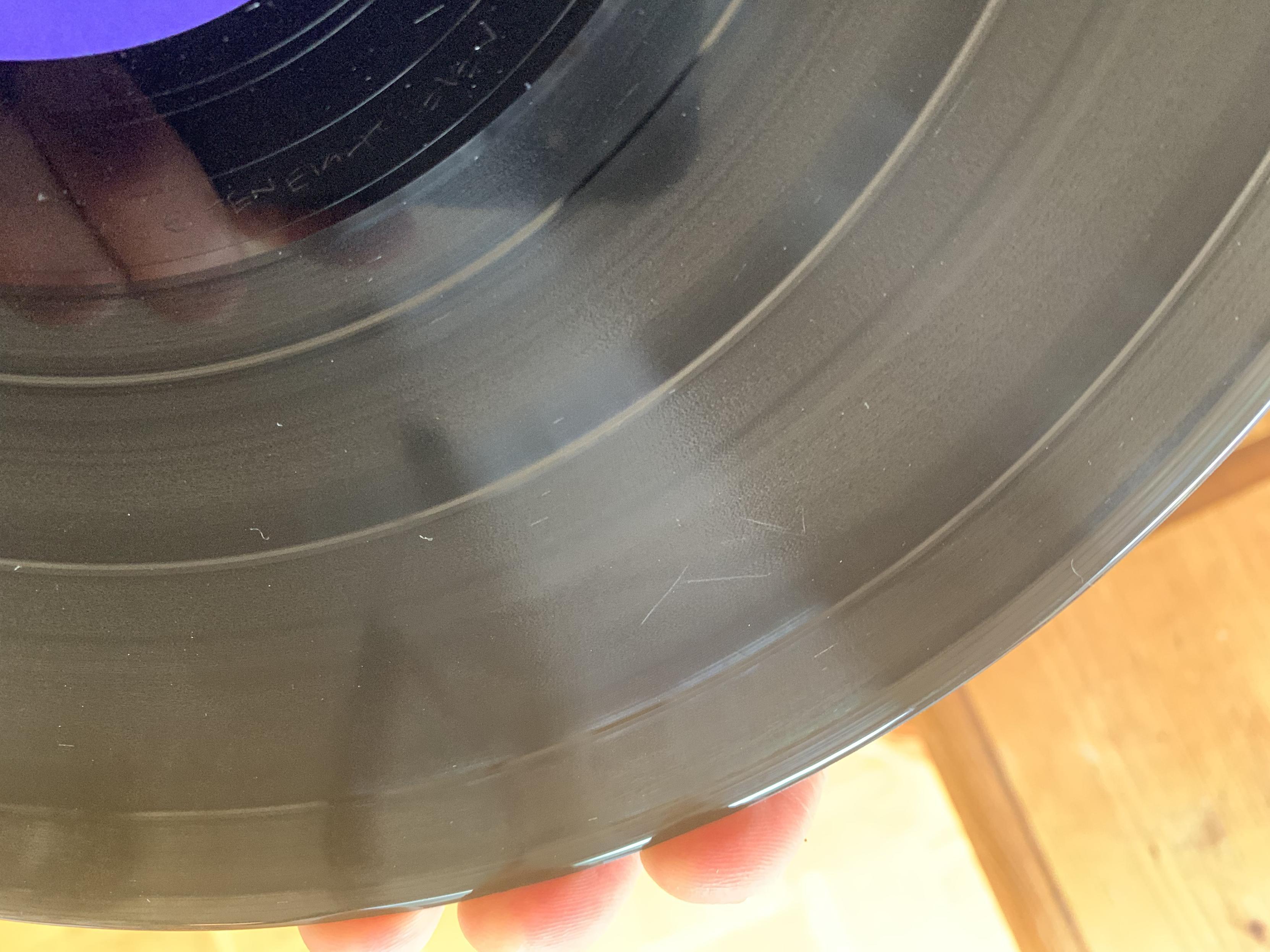 portal of clear vinyl LP (kelly moran — ultraviolet, with scratched surafce—argh!) held on edge by three fingers