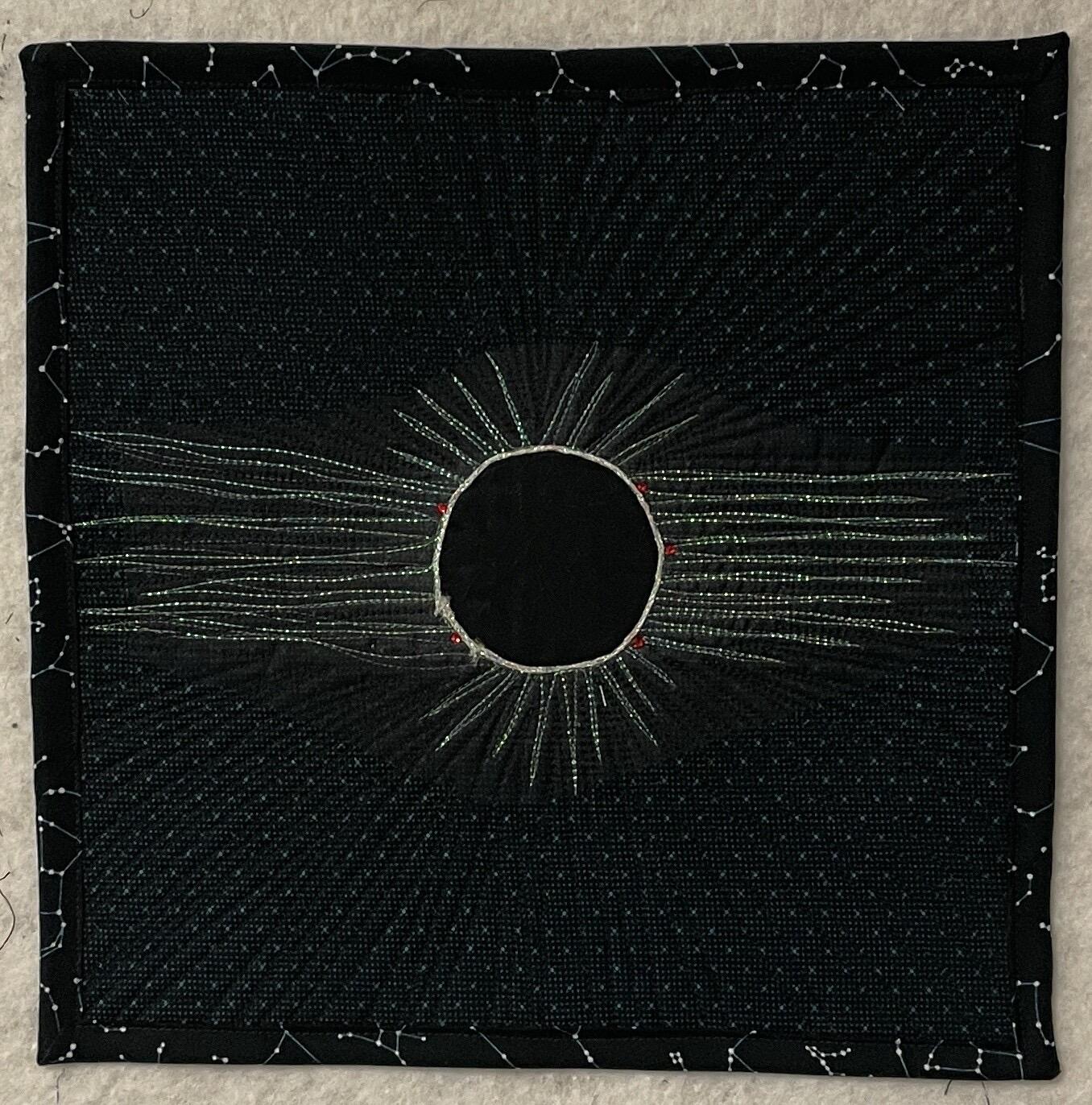 portal of eclipse as fabric art — white circle and rays emerging on black cloth embroidered with white dots, framed by constellation pattern border — artist unknown (that you granny shrimp?)