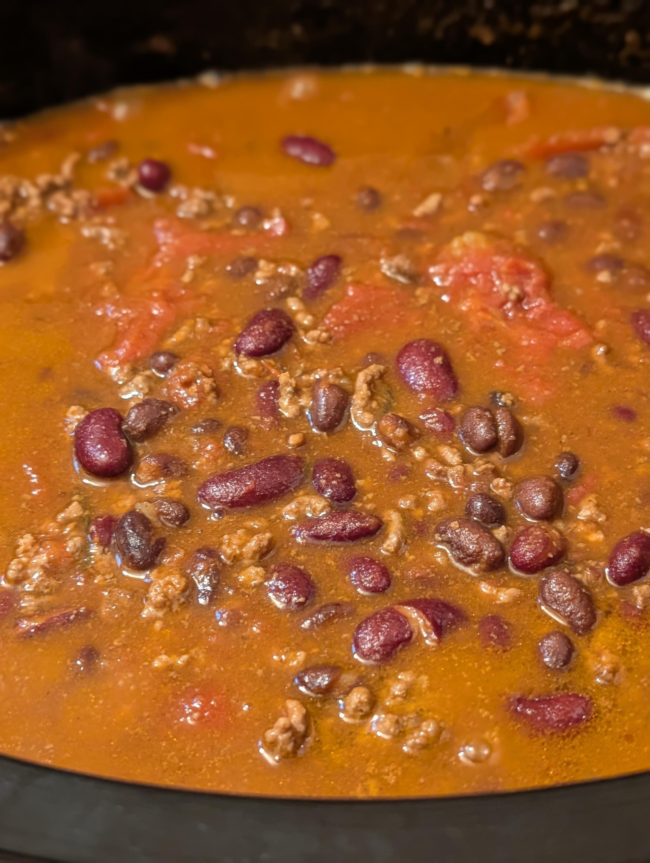 view of chili beans with kidney beans, black beans, tomatoes and sauce in a crock pot.