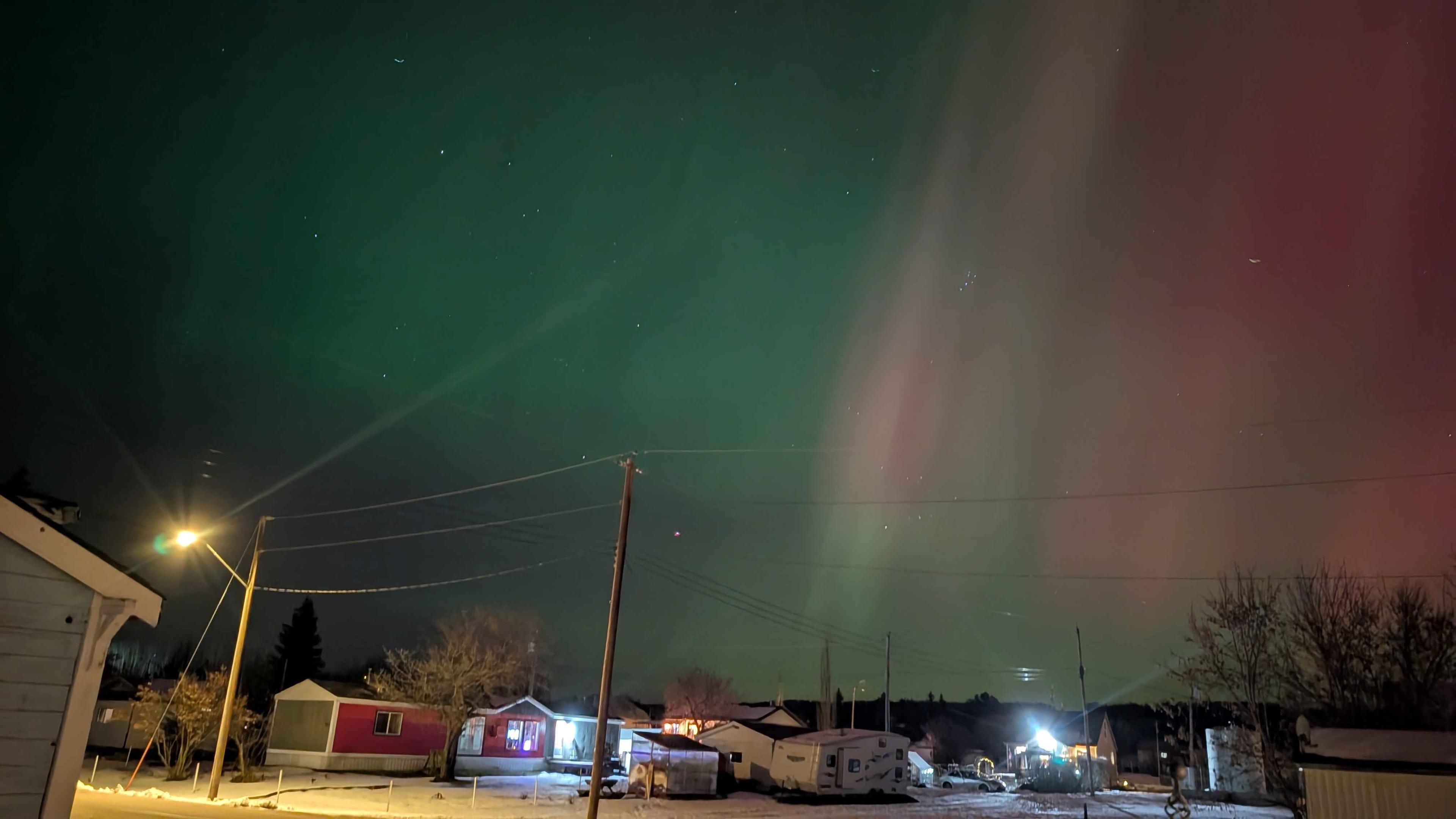 Green and red Aurora borealis over a small community.