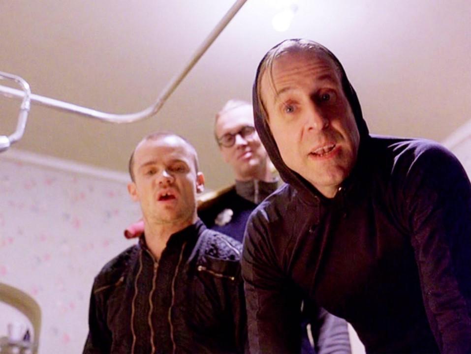 three men dressed in black in a bathroom