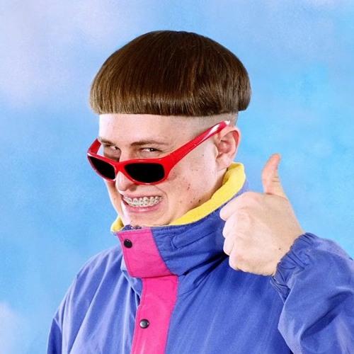 Oliver Tree, a novelty musician with a bowl cut. He is wearing red sunglasses and a purple windbreaker and he is giving the camera a thumbs up.