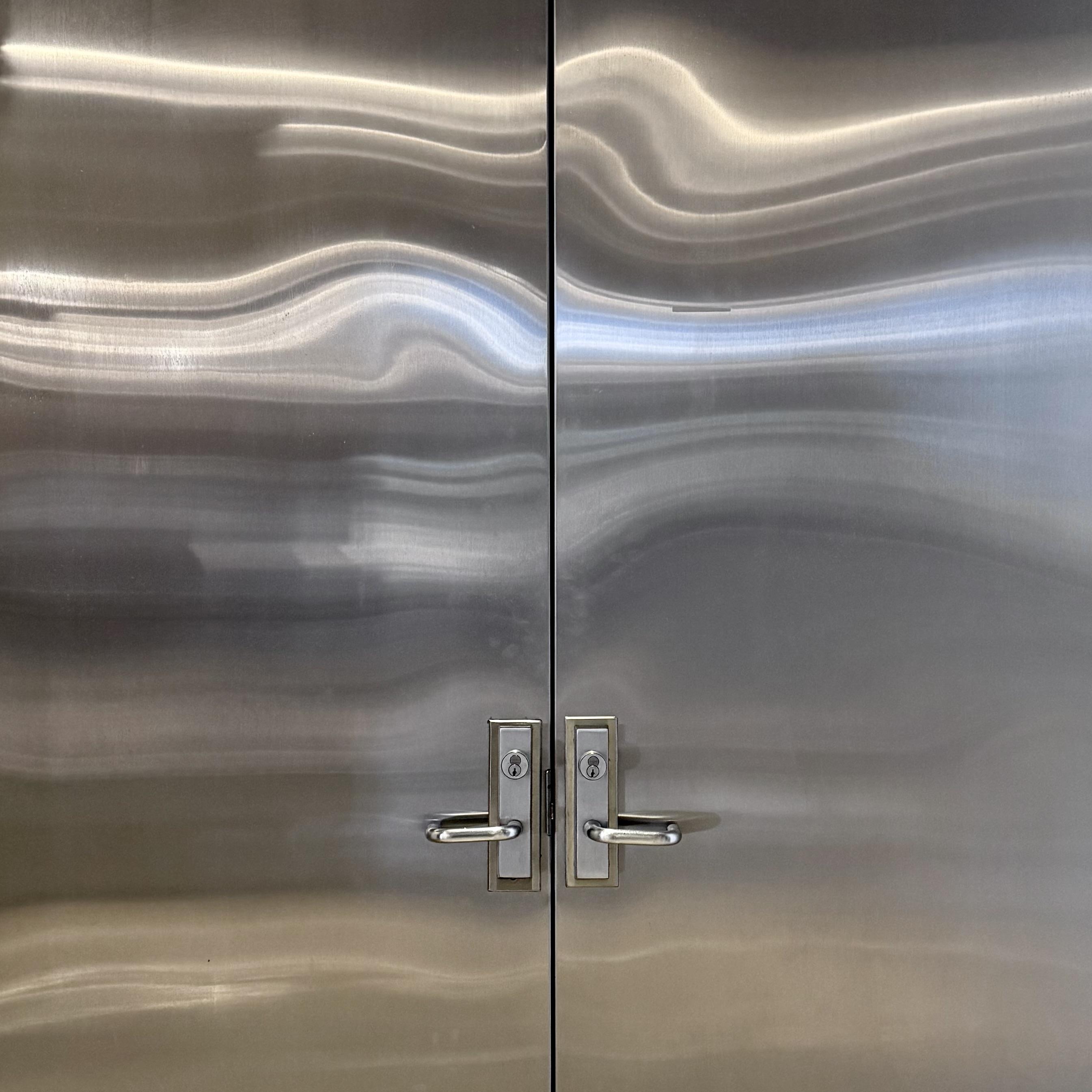 Metal door reflecting nearby lights in a wavy pattern