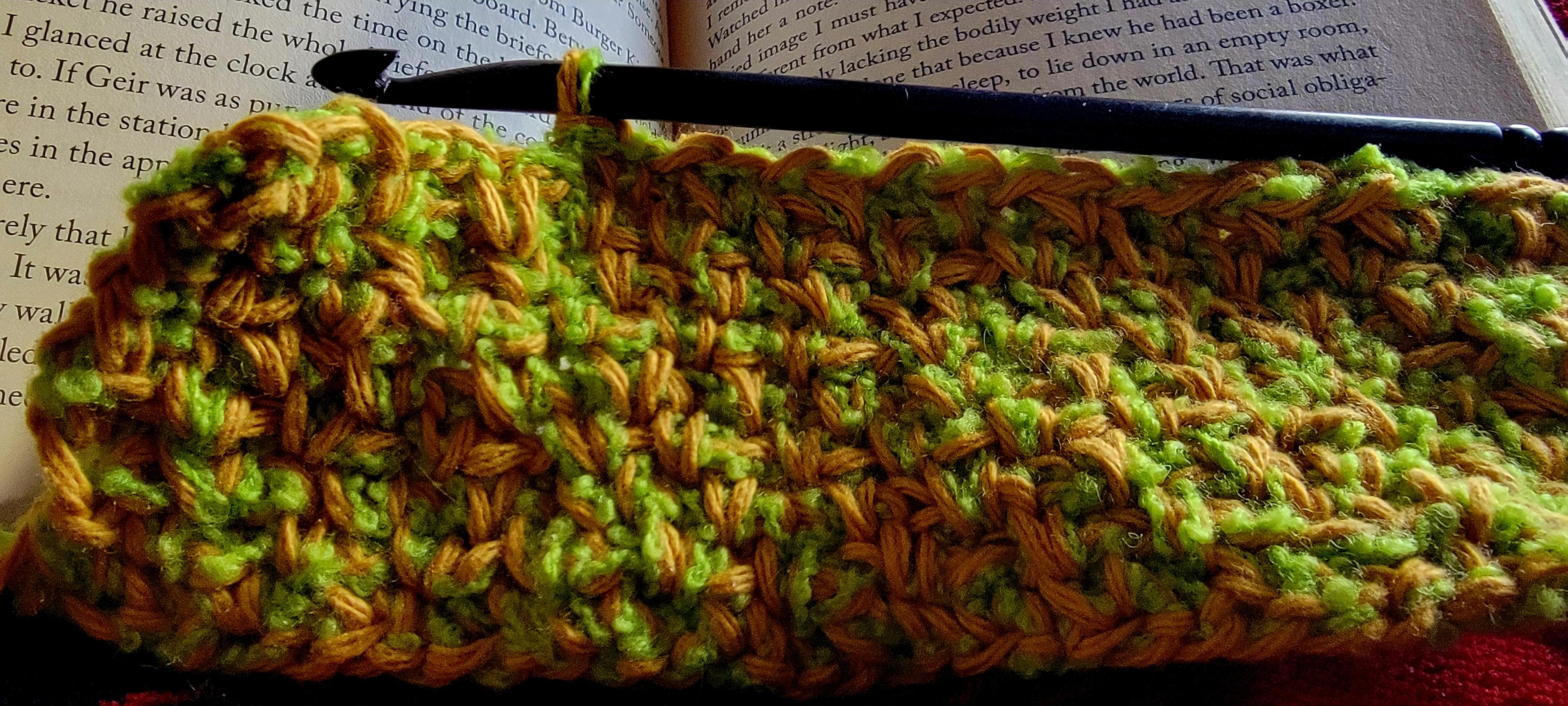 Crocheted potholder in progress, marling green and yellow yarns in moss stitch.