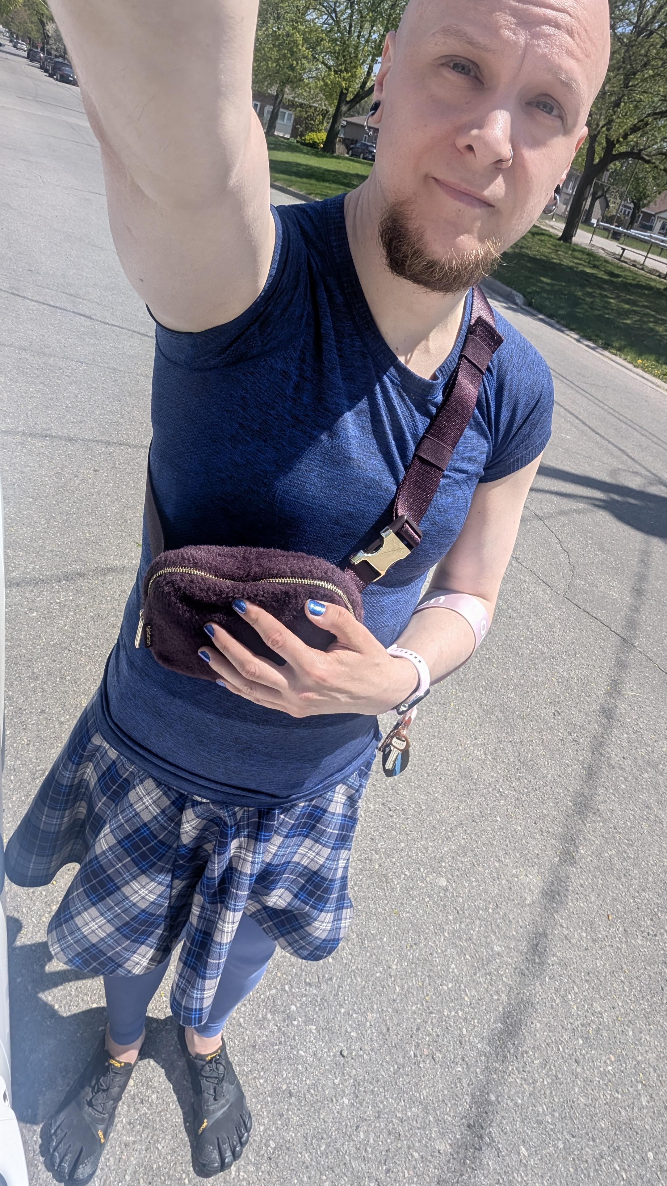 I stand with an arm outstretched in a blue t-shirt, blue plaid skirt, blue leggings, all different shades.
I have a plum coloured crossbody bag and toe shoes