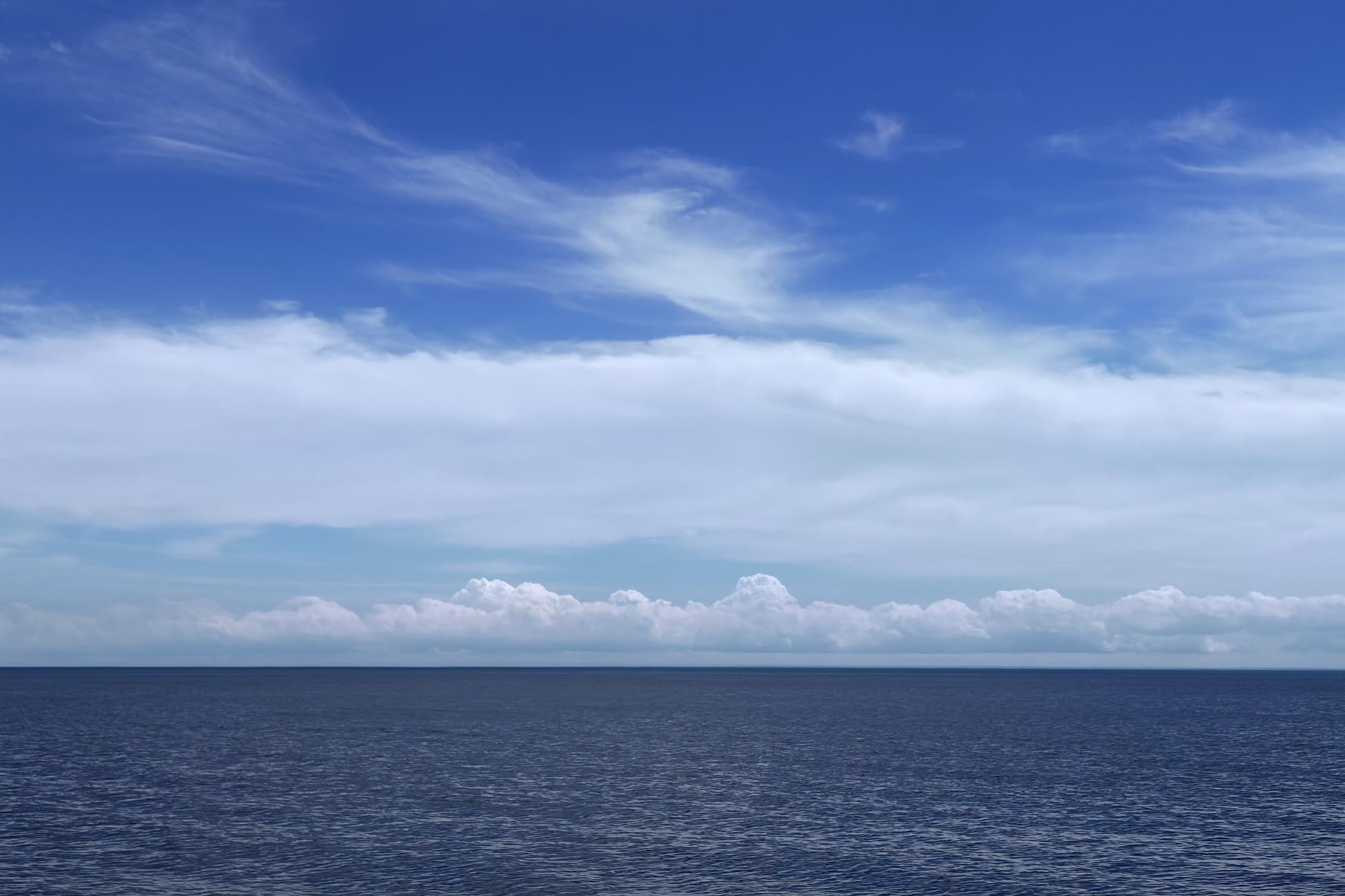 Photograph in three horizontal thirds: at the bottom, the dark blue sea agitated by a few waves; in the middle, white clouds, including a band of cumulus above the horizon and a wider and denser band above; at the top the intense blue sky, the white clouds coming to fray at altitude.

Photographie en trois tiers horizontaux: dans le bas, la mer bleu foncé agitée de quelques vagues; au milieu, des nuages blancs, dont une bande de cumulus au-dessus de l'horizon et une bande plus large et dense au-dessus; en haut le ciel bleu intense, les nuages blancs venant s'effilocher en altitude.