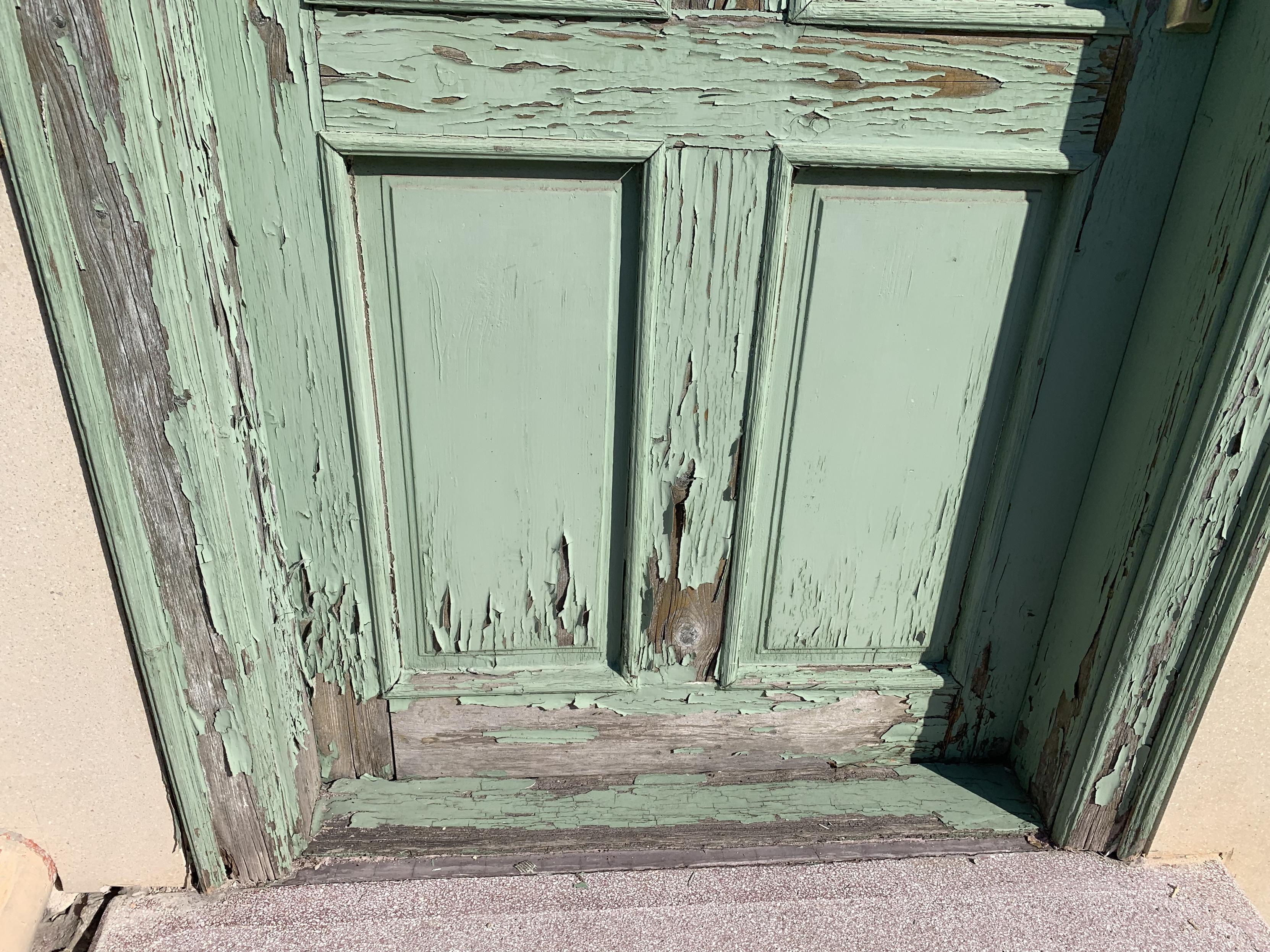 wooden door with panels and chipped blue-green paint