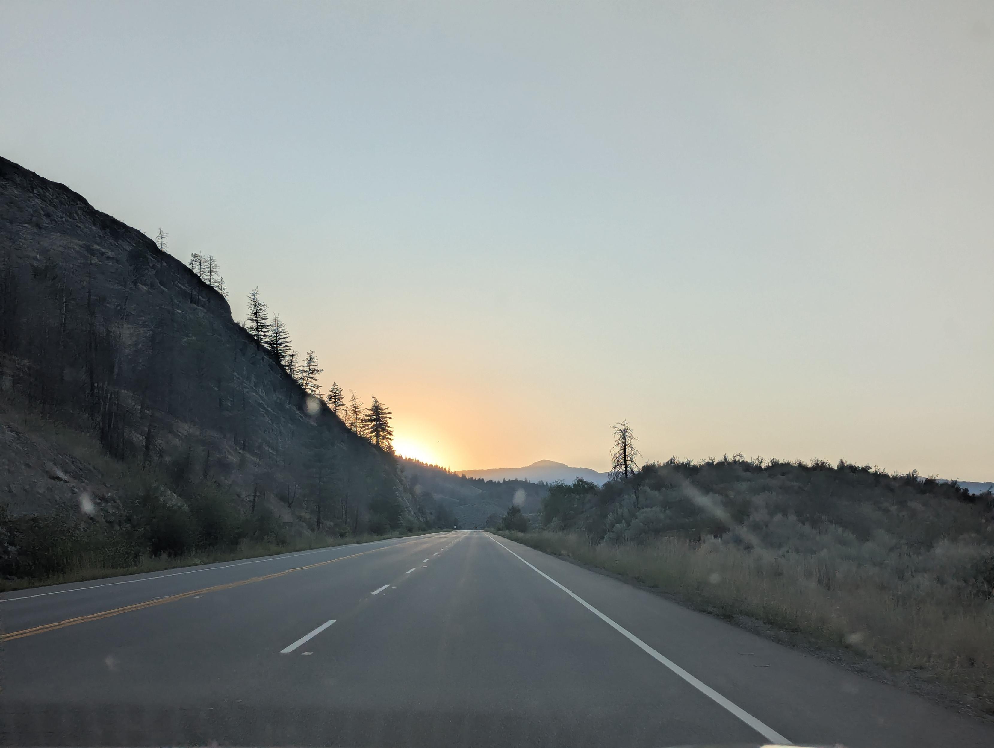 Driving sunset view into the desert mountains. The sky is hazy.