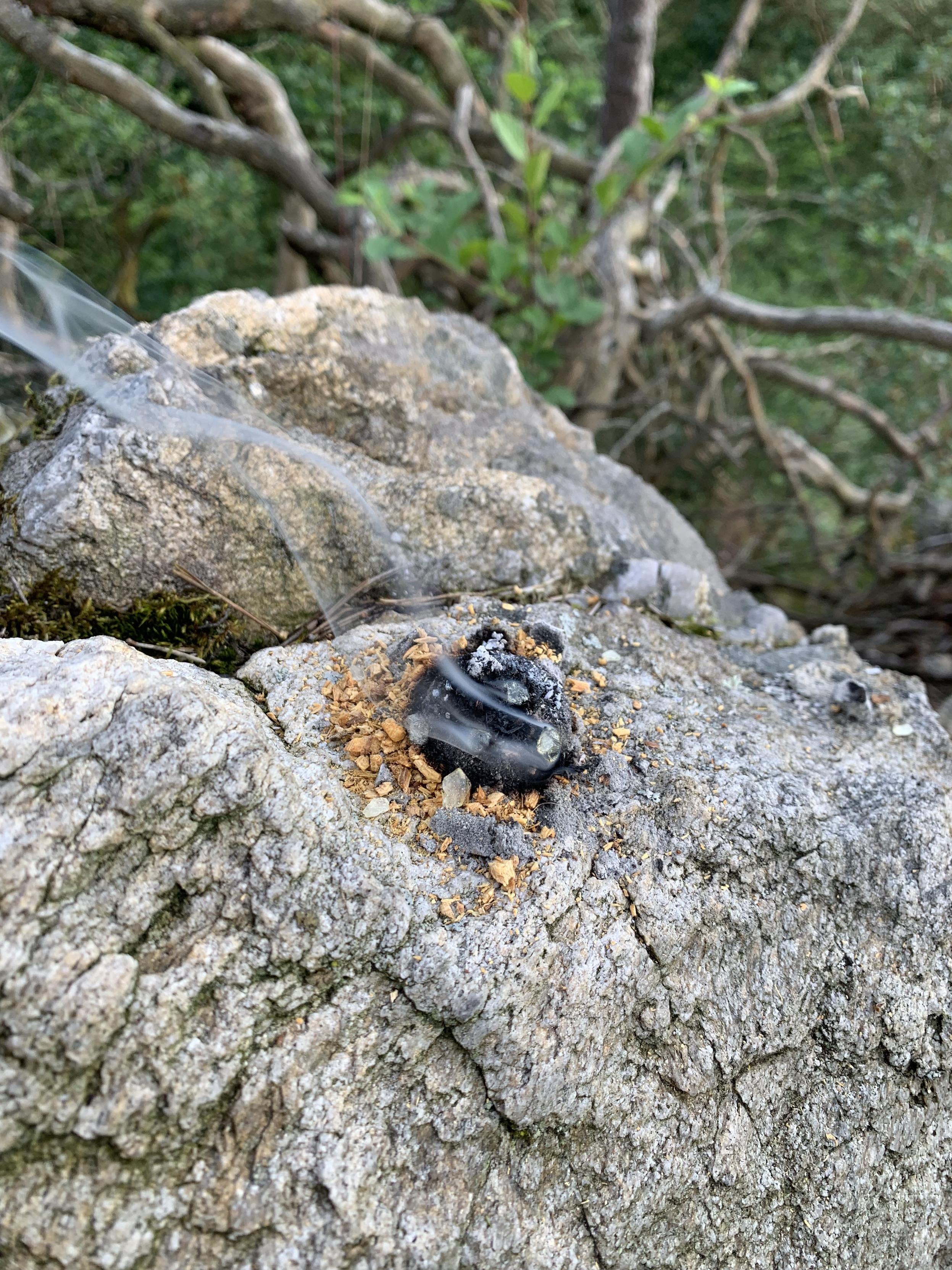 copal and sandalwood being consumed by a swirl of smoke upon charcoal placed on granite