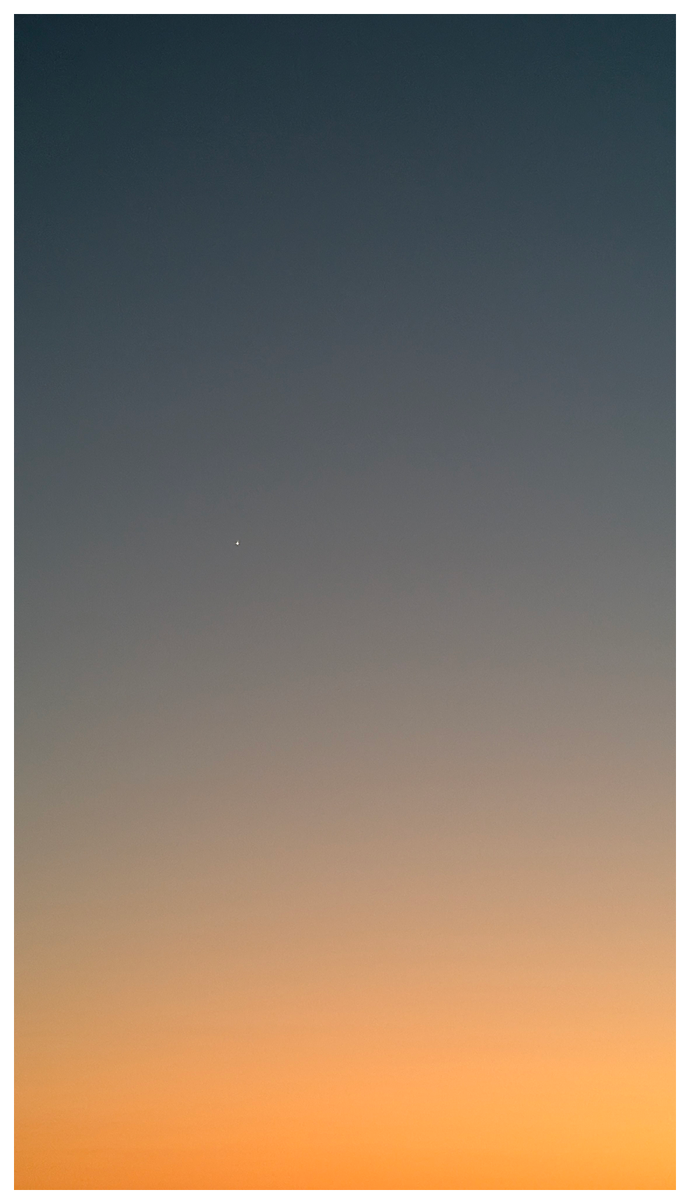 A gradient sky at sunset transitions from deep blue at the top to soft orange at the bottom. A single bright star or planet (Venus?) appears near the upper left of the center.
