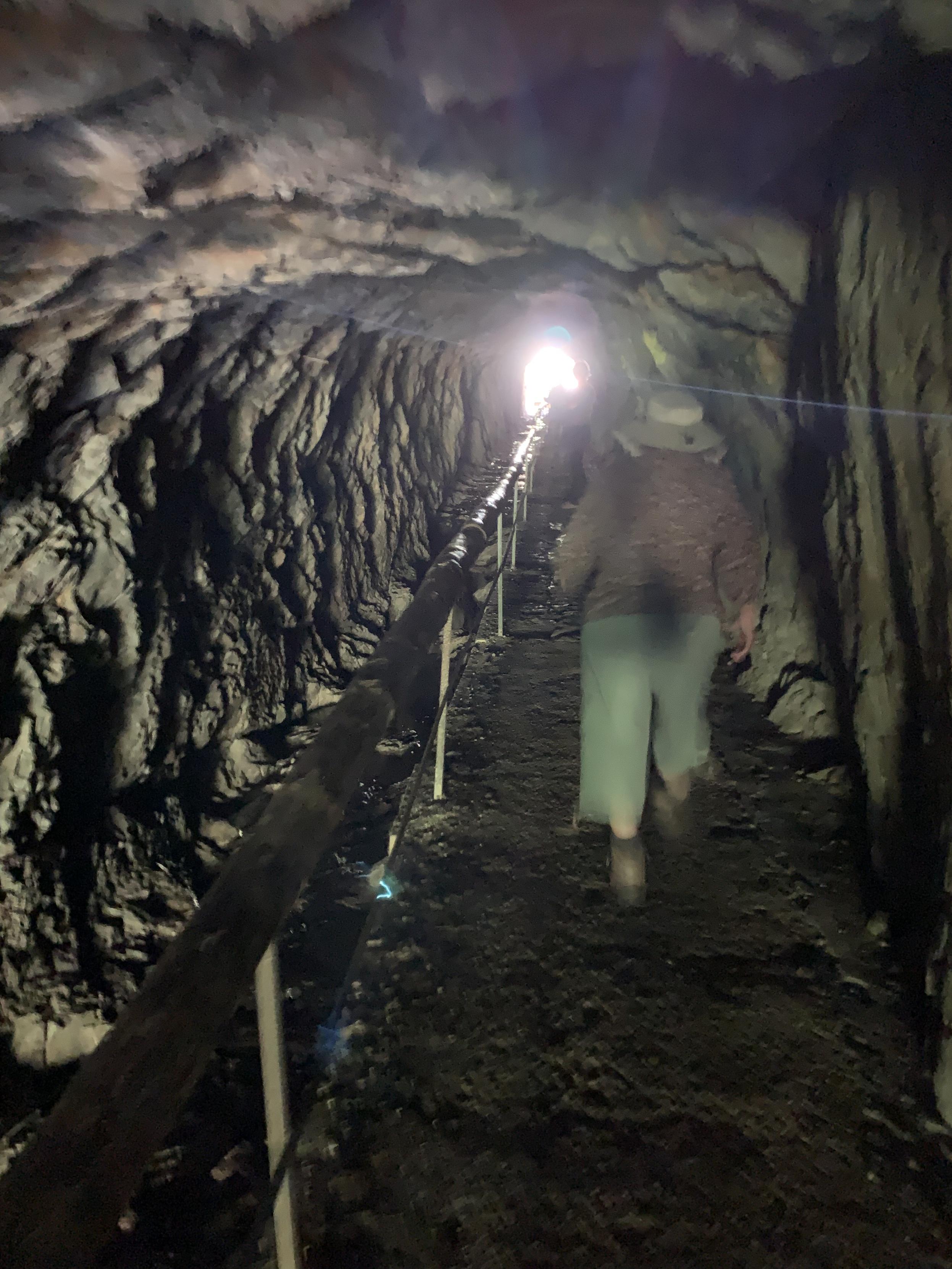 person heading through tunnel through hill of granite — light in the distance