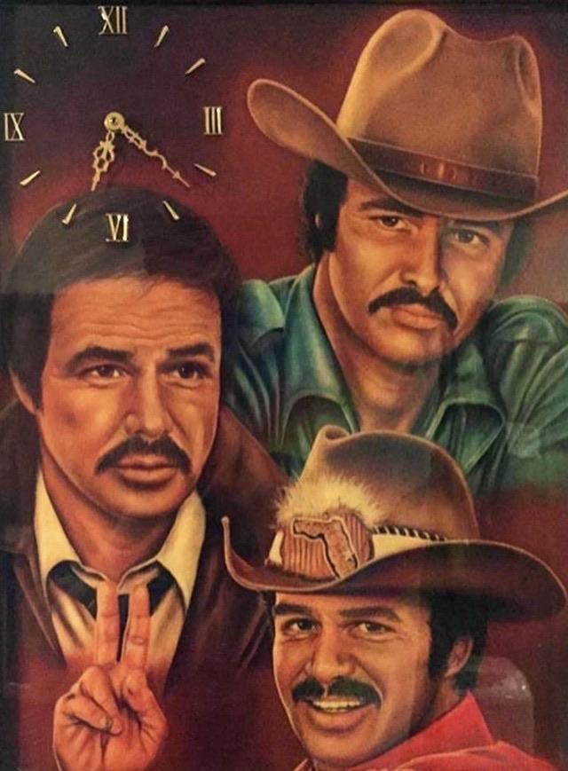 A decorative clock featuring portraits of three men with mustaches. Each man has a distinctive expression and style, with one wearing a cowboy hat. The clock's hands are positioned indicating a time, surrounded by Roman numerals. The background has a warm,